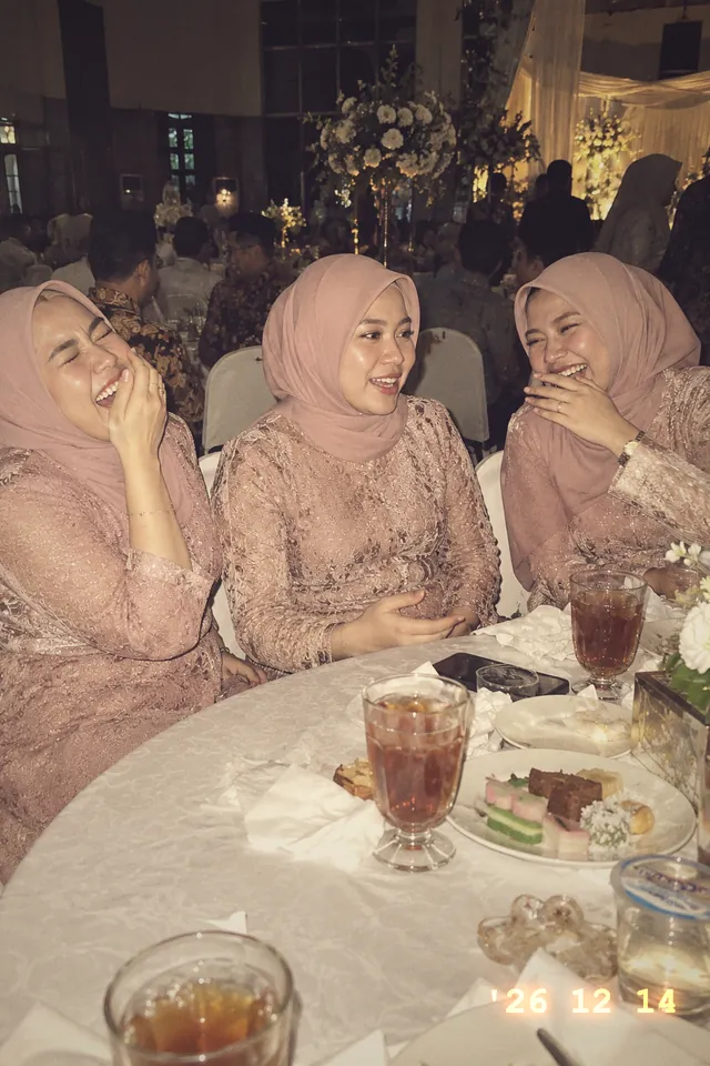 Tiga sahabat Nadia berhijab merah muda tertawa di meja tamu